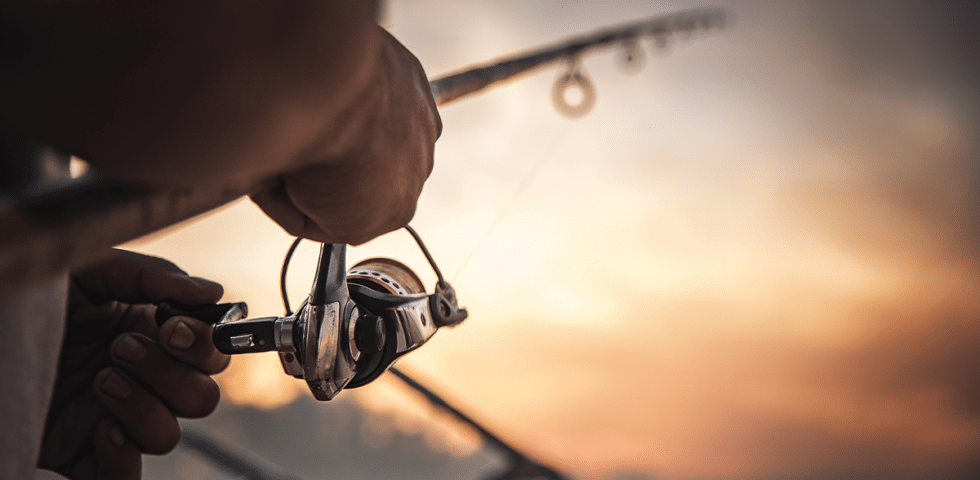 Close up of hand turning fishing reel.