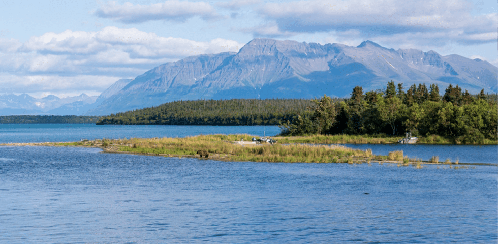 Alaskan coastline with mountains in the background under blow sky.