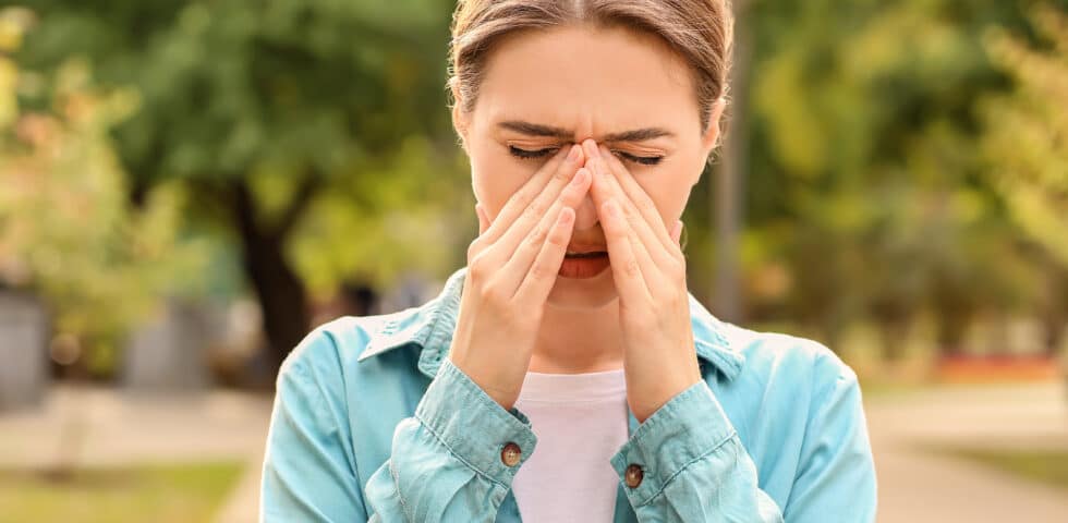 woman holding her nose appearing to have an allergic reaction