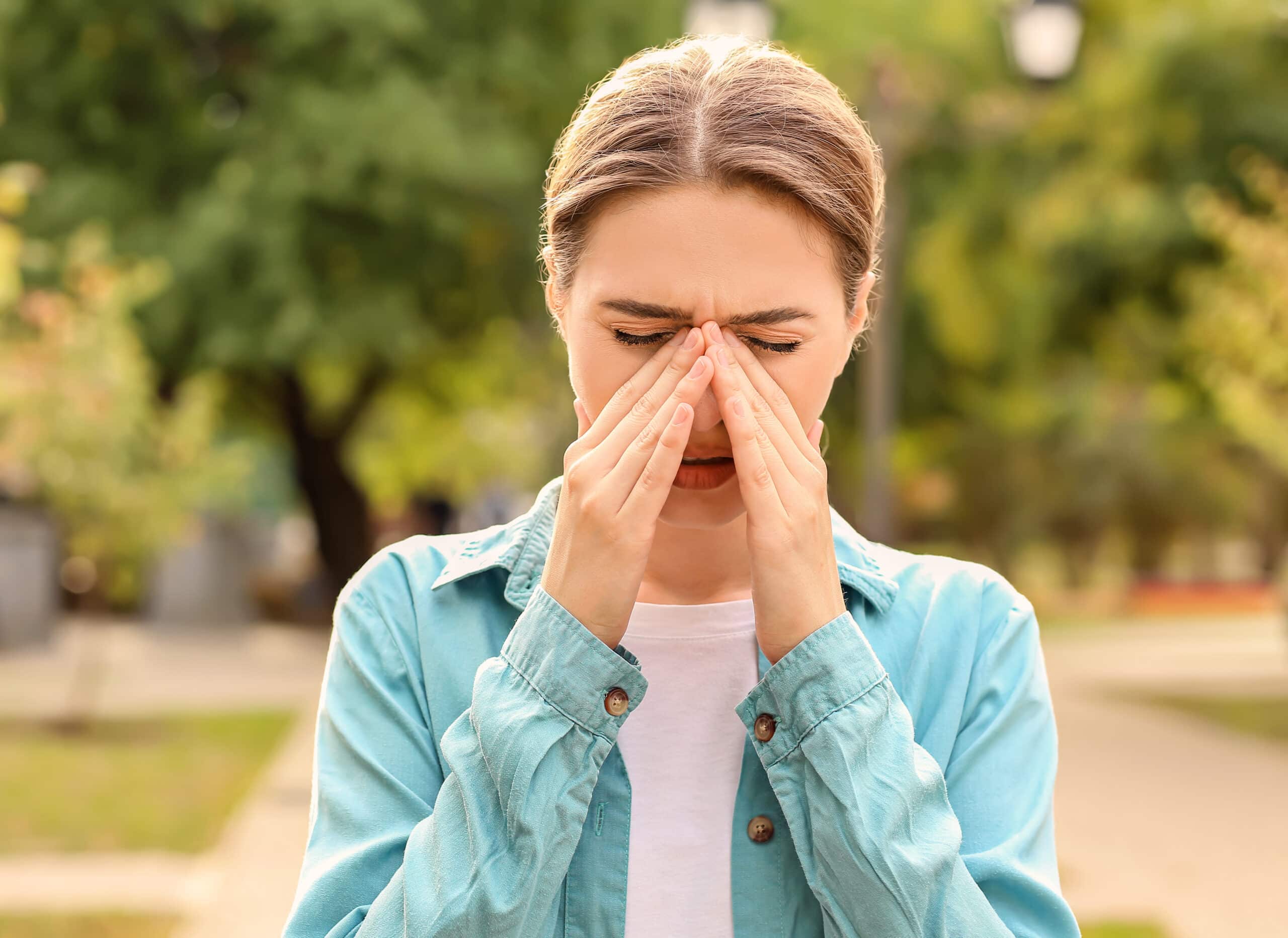 woman holding her nose appearing to have an allergic reaction