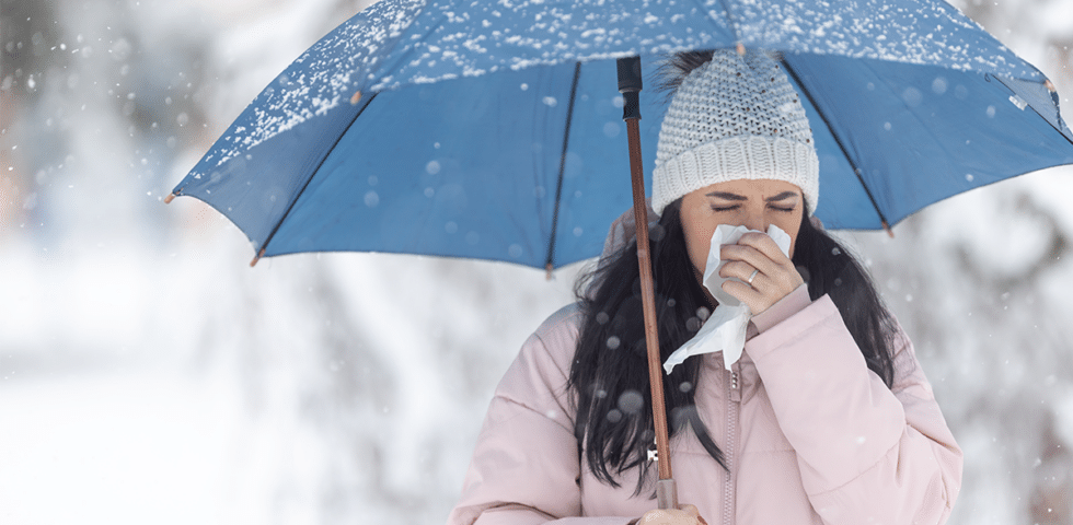 A woman holding an umbrella and blowing her nose.