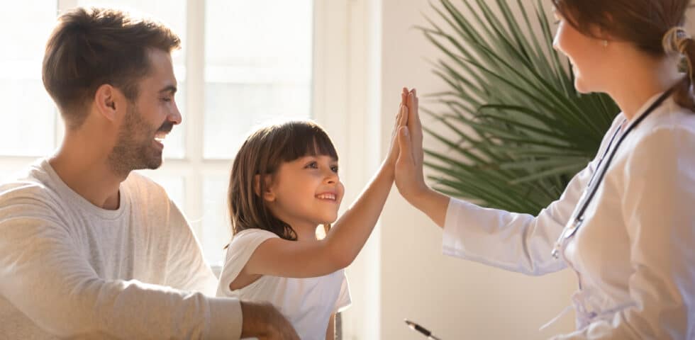 Doctor giving child a high-five at a medical office.